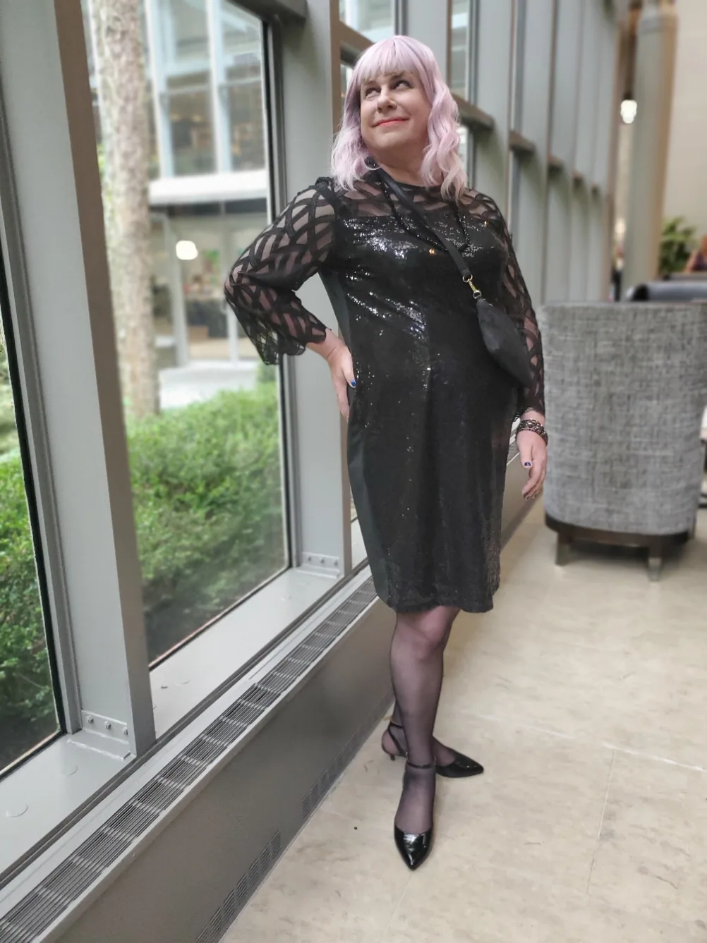 Erika X. Driscoll standing by a wall of windows in a black dress